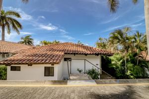 a house with a tile roof and palm trees at Villa Sol 35 & 36 in Playa Hermosa