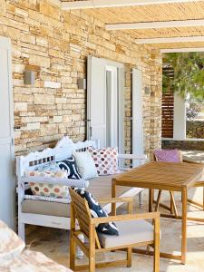 patio con mesa, sillas y pared de ladrillo en Olive Tree Homes, en Ios Chora