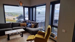 a living room with a couch and large windows at Beautiful penthouse with panoramic view at Sjusjøen in Ringsaker