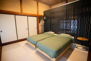 a bedroom with a bed and a black wall at 町宿ORANCHI 