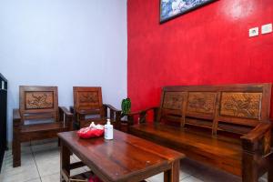 Habitación con bancos de madera y pared roja. en RedDoorz At Pondok Eyang Obi Sleman en Yogyakarta
