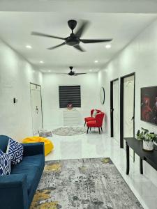 a living room with a blue couch and a ceiling fan at E'dayah Homestay Taman Ria Sungai Petani in Sungai Petani