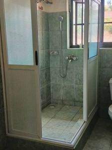 y baño con ducha y puerta de cristal. en 3-Bedroom Mbarara Apartment with Optional Farm Tour, en Mbarara