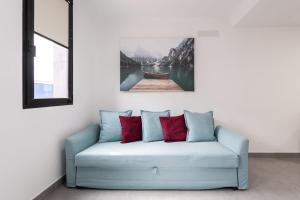 Castillo del Romeral的住宿－APARTAMENTOS BLUE EYES，客房内的蓝色沙发,配有红色枕头