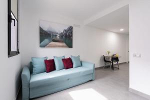 Castillo del Romeral的住宿－APARTAMENTOS BLUE EYES，客厅配有蓝色沙发和红色枕头