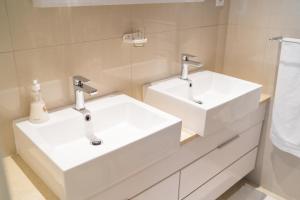 a bathroom with two white sinks and a shower at Studio 1101 iTower in Gaborone +11 photos