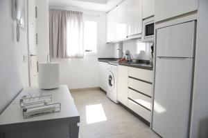 a white kitchen with a refrigerator and a sink at Ático Platero in Nerja
