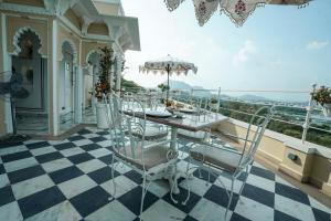 a table and chairs on a balcony with a view at Burj Baneria in Udaipur