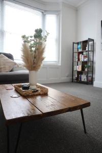 a wooden coffee table with a vase of flowers on it at Spacious 1 bedroom apartment in Leicester