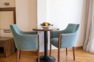 a table with two chairs and a bowl of fruit on it at Golden Bay Beach Hotel in Larnaca
