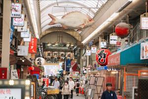 a market with a fish hanging from the ceiling at KUROMON Royal in Osaka