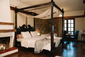 a bedroom with a canopy bed and a fireplace at Pliades Traditional Guesthouse in Palaios Panteleimonas