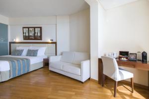 a bedroom with a bed and a chair and a desk at Golden Bay Beach Hotel in Larnaca