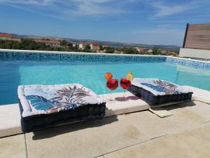 2 sillas y copas de vino junto a la piscina en Villa Scolopax rusticola Skradin with heated pool en Skradin
