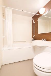 a bathroom with a toilet and a tub and a sink at Hotel New Yokosuka in Yokosuka
