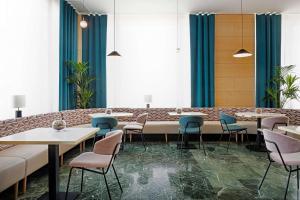 un restaurante con mesas, sillas y cortinas azules en NH Ciudad de Cuenca, en Cuenca