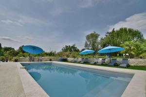 einen Pool mit blauen Sonnenschirmen und Stühlen in der Unterkunft Chambre d'hôtes L'altitude - Domaine la Rose des vents in Castelnau-sur-lʼAuvignon