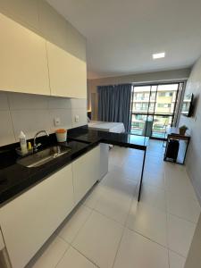 a kitchen with white cabinets and a black counter top at Mana Beach Ohana 208 in Ipojuca