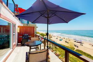 a balcony with a table and an umbrella and a beach at 3009 Ocean Street- Unit C & D in Carlsbad
