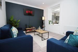 a living room with two blue couches and a table at K Suites - Robert Street in Trehafod