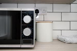 a microwave sitting on a counter next to a trash can at K Suites - Robert Street in Trehafod