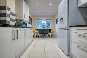 una cocina con armarios blancos y una mesa con sillas amarillas en K Suites - The Villas en Birmingham