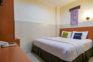 ein Hotelzimmer mit einem großen Bett mit zwei Kissen in der Unterkunft Urbanview Hotel 58 Bintaro by RedDoorz in Pondoklang