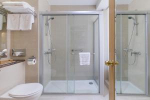 a bathroom with a glass shower with a toilet at Golden Bay Beach Hotel in Larnaca