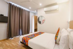 Schlafzimmer mit einem Bett und einem Spiegel in der Unterkunft FabExpress Hexa Meera Bagh in Neu-Delhi