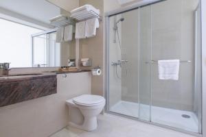 a bathroom with a toilet and a glass shower at Golden Bay Beach Hotel in Larnaca