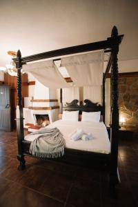 a bedroom with a canopy bed with towels on it at Pliades Traditional Guesthouse in Palaios Panteleimon
