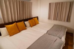 1 cama con almohadas de color naranja y blanco en una habitación en Liaison Court Universal Gateway - Free Parking en Osaka
