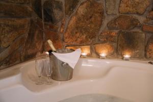 a bath tub with a bucket and glasses and candles at Pliades Traditional Guesthouse in Palaios Panteleimon