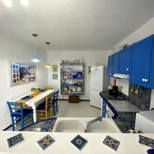 cocina con armarios azules, mesa y nevera en Casa Santorini, en Ribeira Brava