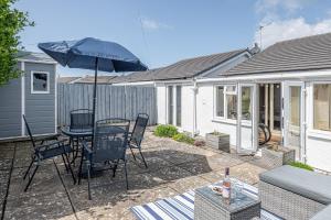 a patio with a table and chairs and an umbrella at Tan Y Wylan in Rhosneigr