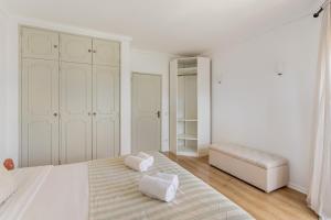 a white bedroom with a bed and a couch at ALTIDO Bright bohemian flat in Cascais in Cascais