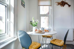 a white table with chairs and a table with food on it at Pebbles In Budleigh in Budleigh Salterton