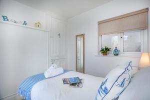 a white bedroom with a bed and a window at Pebbles In Budleigh in Budleigh Salterton