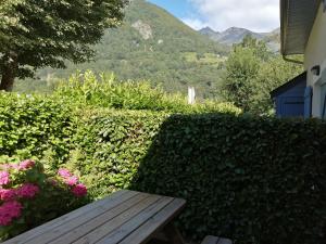 a wooden bench sitting in front of a hedge with flowers at Appartement type chalet 2 chambres avec terrasse in Cauterets