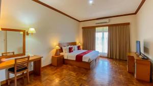 ヌサドゥアにあるLangon Bali Resort by The Lavanaのベッド、デスク、鏡が備わる客室です。
