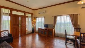 ein Wohnzimmer mit einem Tisch und einem Schreibtisch mit einem TV in der Unterkunft Langon Bali Resort by The Lavana in Nusa Dua