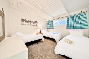 two beds in a room with white walls at Seascape Compound in Newport Beach