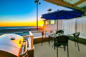 un patio con mesa, sombrilla y tabla de surf en Seascape Compound, en Newport Beach
