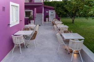 una fila di tavoli e sedie accanto a un edificio viola di Ideal Boutique Hotel a Párga