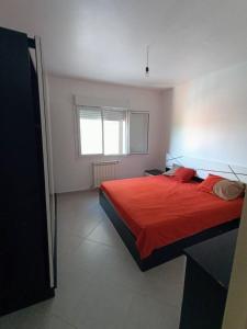 um quarto com uma cama vermelha e uma janela em Bienvenus à Bejaia F3 6p em Bejaïa