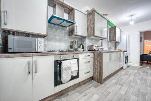 a kitchen with white appliances and wooden cabinets at K Suites - Madeley Road in Birmingham