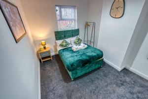 a bedroom with a green bed and a clock on the wall at K Suites - Madeley Road in Birmingham