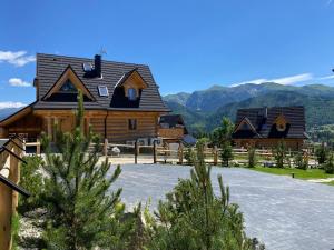 a large log cabin with mountains in the background at Villa Royal Zakopane in Kościelisko