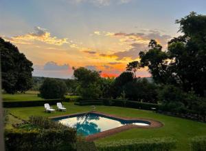 una piscina in un cortile con un tramonto sullo sfondo di Bannockburn Guest Cottage a White River Altre 4 foto