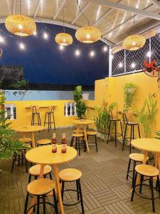 a restaurant with tables and stools and a yellow wall at Saigon Authentic Hostel - Cozy Rooftop, Family Cooking Experience, FREE Walking Tour, Vietnamese Breakfast & Gym in Ho Chi Minh City